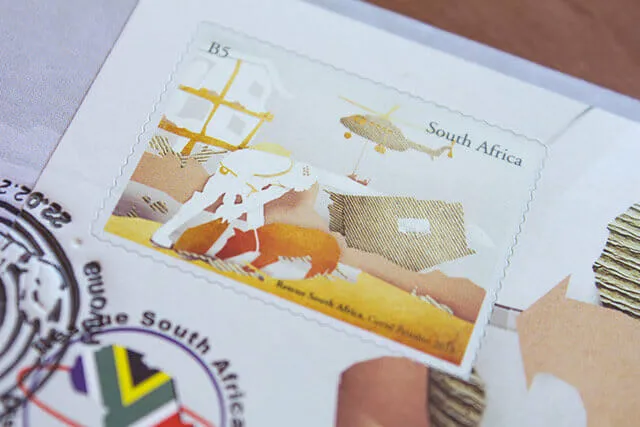 The helicopter stamp photographed at a low angle on the envelope, with the Rescue South Africa emblem and part of a postmark visible below it.